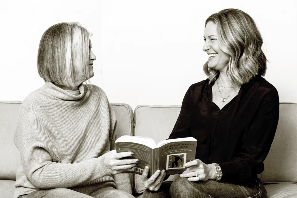 Shannon and Cara laughing while reading a book